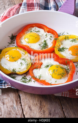 fried eggs with yellow and red peppers in a pan close-up. vertical Stock Photo