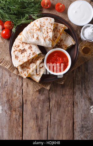 Quesadilla sliced with vegetables and sauce on a plate. vertical top view Stock Photo