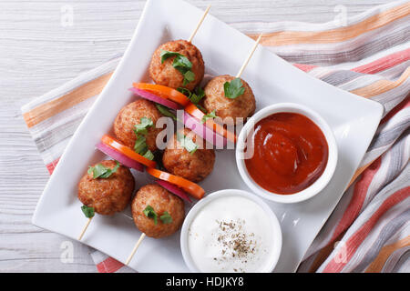 meatballs on skewers with vegetables and sauce on a plate close-up. horizontal view from above Stock Photo