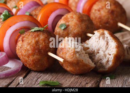 Roasted meat cutlets on skewers with vegetables on an old table close-up, horizontal Stock Photo