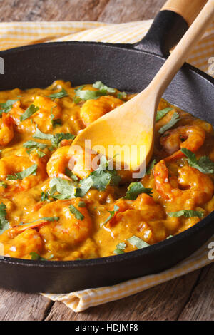 Prawns in curry sauce in a black frying pan close-up. vertical Stock Photo