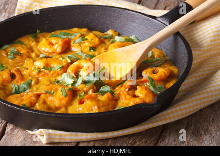 Prawns in curry sauce in a black frying pan close-up. Horizontal Stock Photo