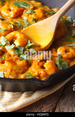 Prawns in curry sauce in a black frying pan macro. vertical, rustic style Stock Photo