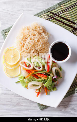 Rice noodle and vegetable salad on a plate on a wooden table with ...