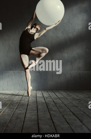 Inspired young gymnast stretching using the white ball Stock Photo