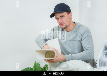 young technician installing air conditioning system indoors Stock Photo