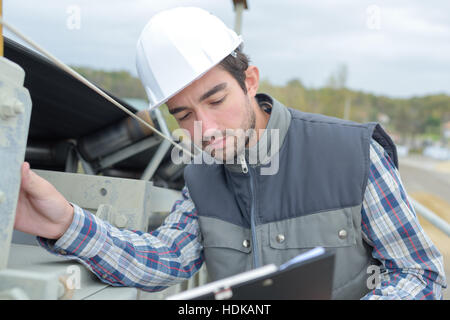 Man on construction site consulting clipboard Stock Photo