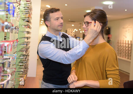 ophthalmologist and beautiful brunette female choosing glasses in optics store Stock Photo