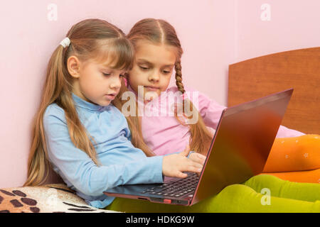 Two girls pushing a search query on a laptop keyboard Stock Photo