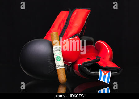 Red and black boxing gloves and luxury Cuban cigars on black glass table. Stock Photo