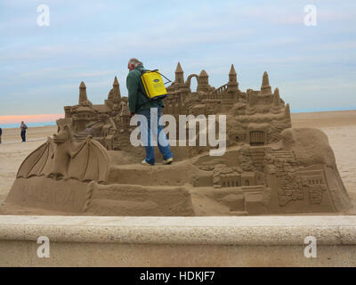 Man damping down a fantasy sand sculpture on the beach at Valencia, Spain Stock Photo