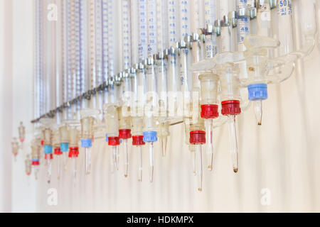 Glass burettes hanging at chemistry wall in high school Stock Photo