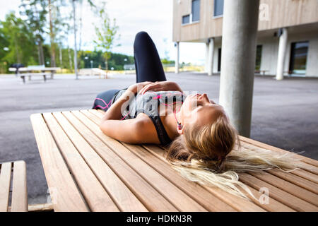 Sporty Woman Listening Music While Resting On Bench Stock Photo