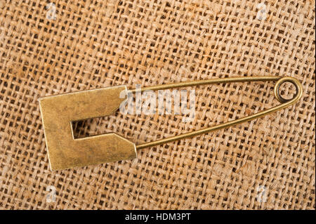 Vintage brooch or safety pin on jute background, Stock Photo