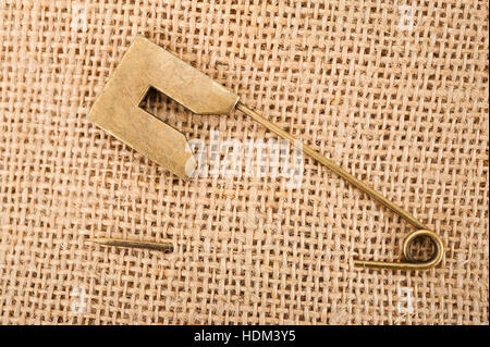 Vintage brooch or safety pin on jute background, Stock Photo