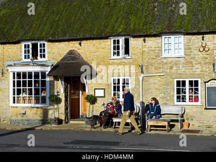 People enjoying a drink outside the Three Horseshoes pub in the village of Burton Bradstock, Dorset, England UK Stock Photo