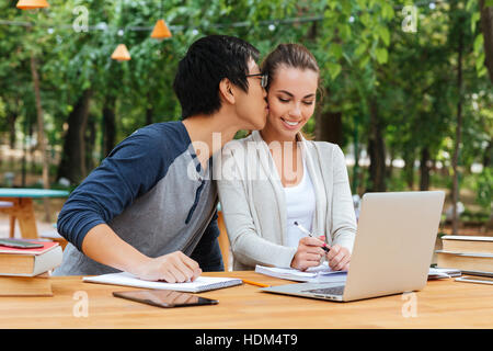 Happy young couple studying and kissing in outdoor cafe Stock Photo