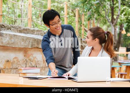 Handsome asian man teaching pretty young woman outdoors Stock Photo