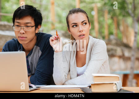 Thoughtful young couple using laptop and studying together Stock Photo