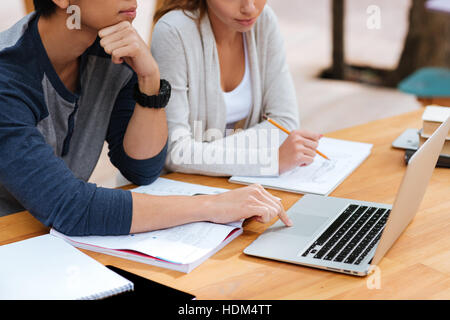 Closeup of serious young couple with laptop sitting and writing together Stock Photo