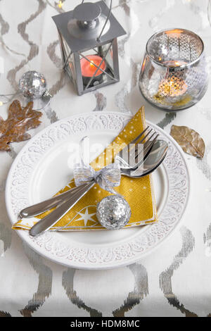 Festive table setting for Christmas holiday with decorations, candles, fork and spoon and ornaments Stock Photo