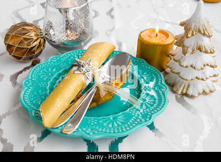 Festive table setting for Christmas holiday with decorations, candles, fork and spoon and ornaments Stock Photo