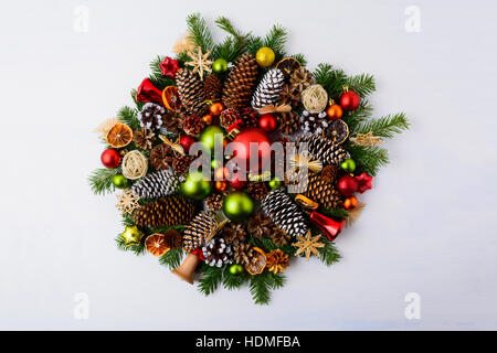 Christmas wreath with fir branches, pine cones and rustic ornaments. Christmas decoration with baubles, jingle bells and dried orange slices. Stock Photo