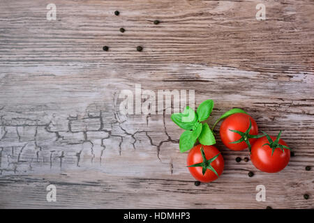 Three tomatoes and pepper groups with basil on the wooden table, view from above. Stock Photo