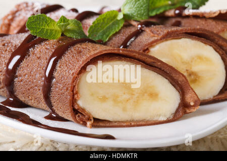 Chocolate crepes with banana filling macro on a white plate. horizontal Stock Photo