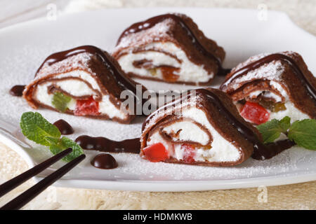 Japanese chocolate crepe rolls with cheese and fruit on a white plate close-up. horizontal Stock Photo