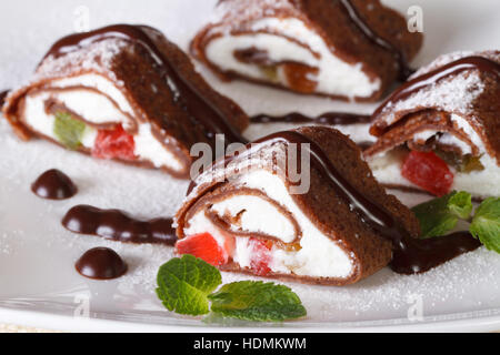 chocolate crepe rolls with cheese, fruit and mint on a white plate close-up. horizontal Stock Photo