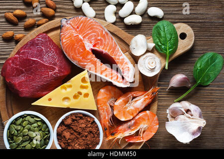 Foods High in Zinc as salmon, seafood-shrimps, beef, yellow cheese, spinach, mushrooms, cocoa, pumpkin seeds, garlic, bean and almonds. Top view Stock Photo