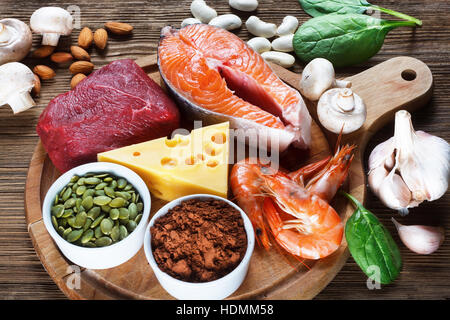Foods High in Zinc as salmon, seafood-shrimps, beef, yellow cheese, spinach, mushrooms, cocoa, pumpkin seeds, garlic, bean and almonds. Top view Stock Photo