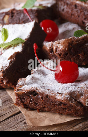 Delicious chocolate brownie cake with cherry closeup on paper. Vertical Stock Photo