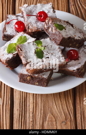 chocolate cake brownies with walnuts on a white plate. Vertical close-up Stock Photo