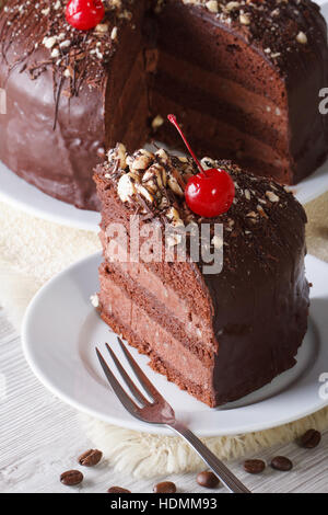 Cut a piece of chocolate cake with cherries on a plate. Vertical close-up Stock Photo