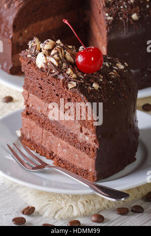 Cut a piece of dark chocolate cake with cherries macro. vertical Stock Photo
