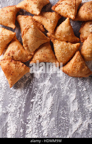 A pile of baking samosas on a floured table. vertical top view closeup Stock Photo