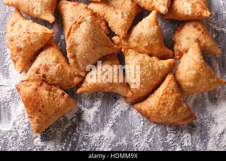 A pile of baking samosas on a floured table. horizontal top view close-up Stock Photo