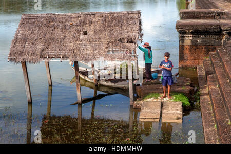 Khmer Cambodian boy and his mother fish and collect pond weeds in the moat in front of Angkor Wat, Kingdom of Cambodia. Stock Photo
