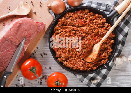 Bolognese sauce cooking in a frying pan and ingredients on the table. horizontal view from above Stock Photo