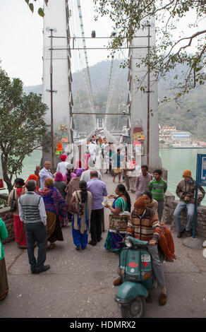 People crossing Laxman Jhula bridge over Ganges river in Rishikesh,India. Stock Photo