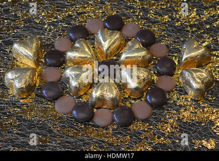 Chocolate decadence. Gold foil covered chocolate hearts with milk and dark chocolate drops. Stock Photo