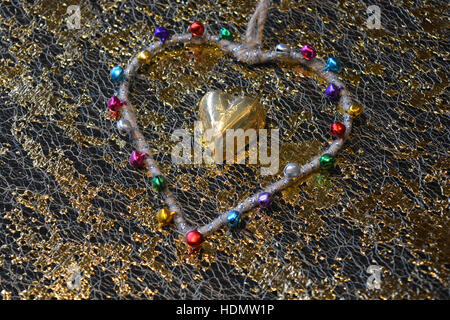 Gold foil covered chocolate heart surrounded by a heart shape with bells Stock Photo