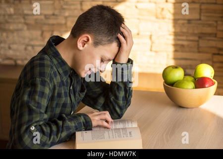 Young Boy Reading Book and Studying on Table at Home Stock Photo