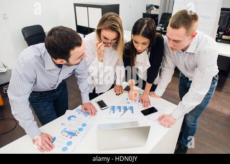 Colleagues at an office meeting talking and working on a laptop Stock Photo
