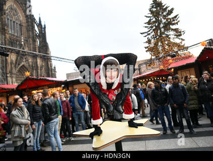Cologne, Germany. 12th Dec, 2016. Contortionist Alina Ruppel shows off her skills on a table at the Christmas market in Cologne, Germany, 12 December 2016. Ruppel is due to compete in the final of RTL talent show Das Supertalent on 17 December. Photo: Henning Kaiser/dpa/Alamy Live News Stock Photo