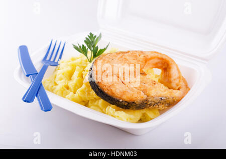 Fried fish with mashed potatoes on plastic plate and blue fork and knife Stock Photo