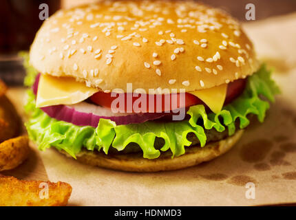 Fresh tasty burger and french fries on served paper close-up on restaurant table Stock Photo