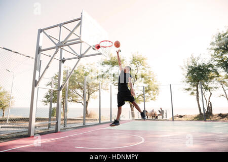 Photo of basketball player practicing and posing for basketball and sports athlete concept. Looking at basketball hoop. Stock Photo